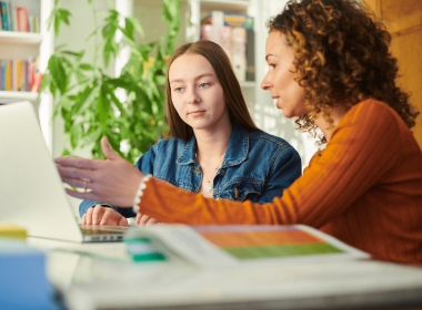 Young person working with teacher on a laptop