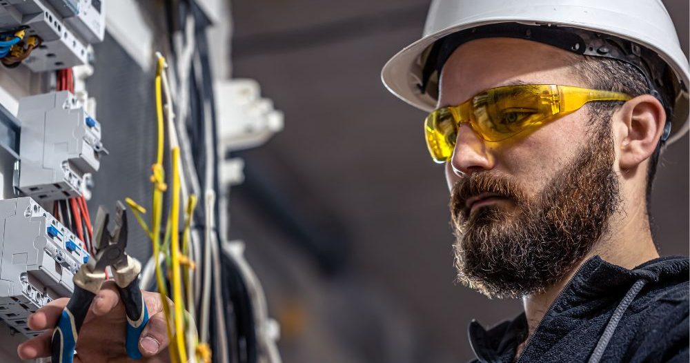 Man In A Hard Hat And Safety Glasses Working On An Electrical Panel