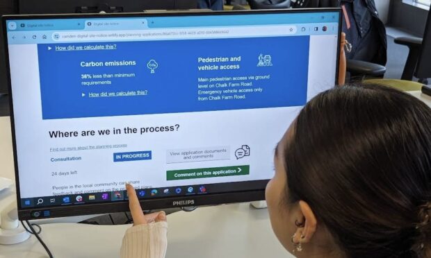 a woman looking at a computer screen which displays information saying where she is in the process of submitting a planning application