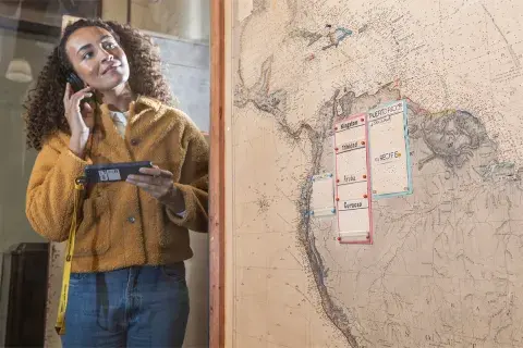 A person stands next to a map from the Second World War whilst listening to an audio guide