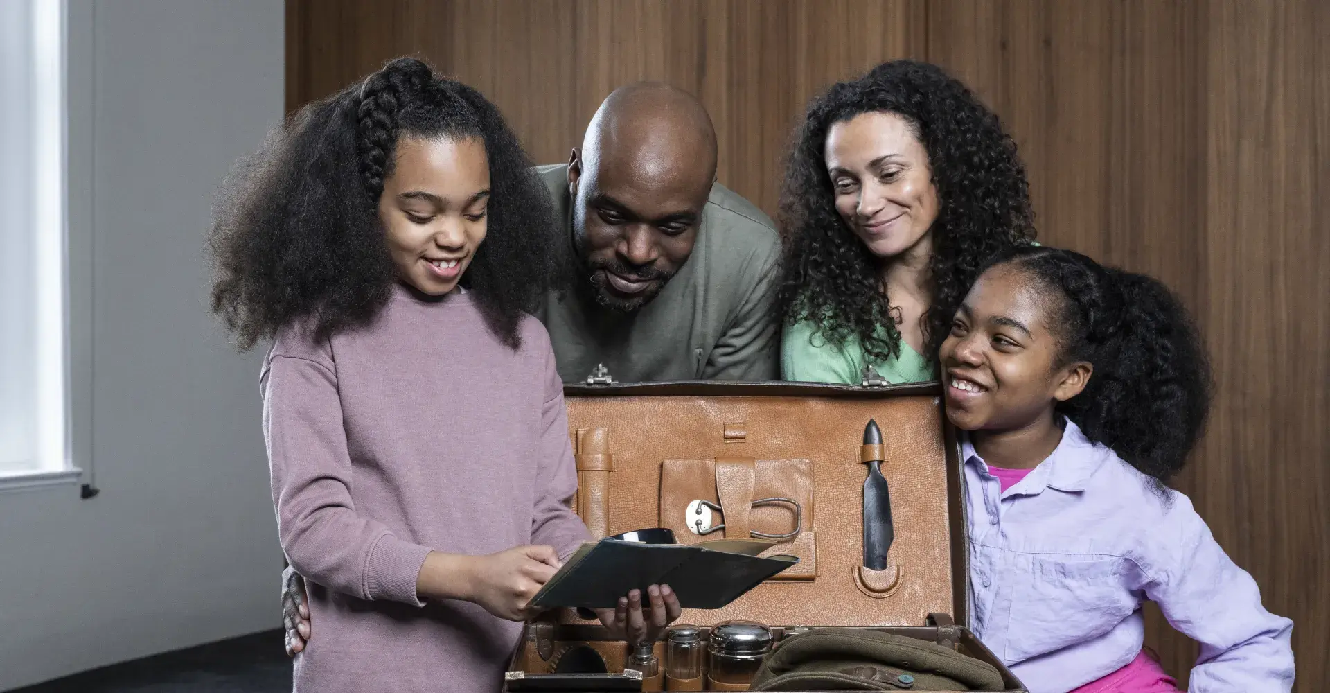 A family examines a suitcase which features IWM collections items 