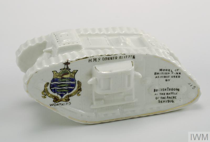 White ceramic tank showing the crest of Worthing on the side and the words "H.M.S. Donner Ritzen Model of British Tank as first used by British Troops at the Battle of the Ancre Sep. 1916".