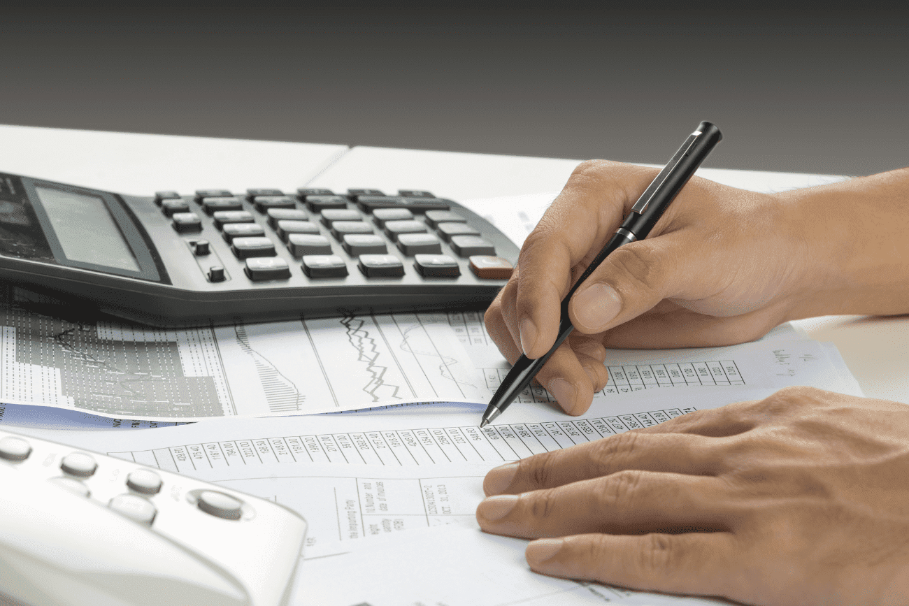 Man Writing On Paper With A Calculator