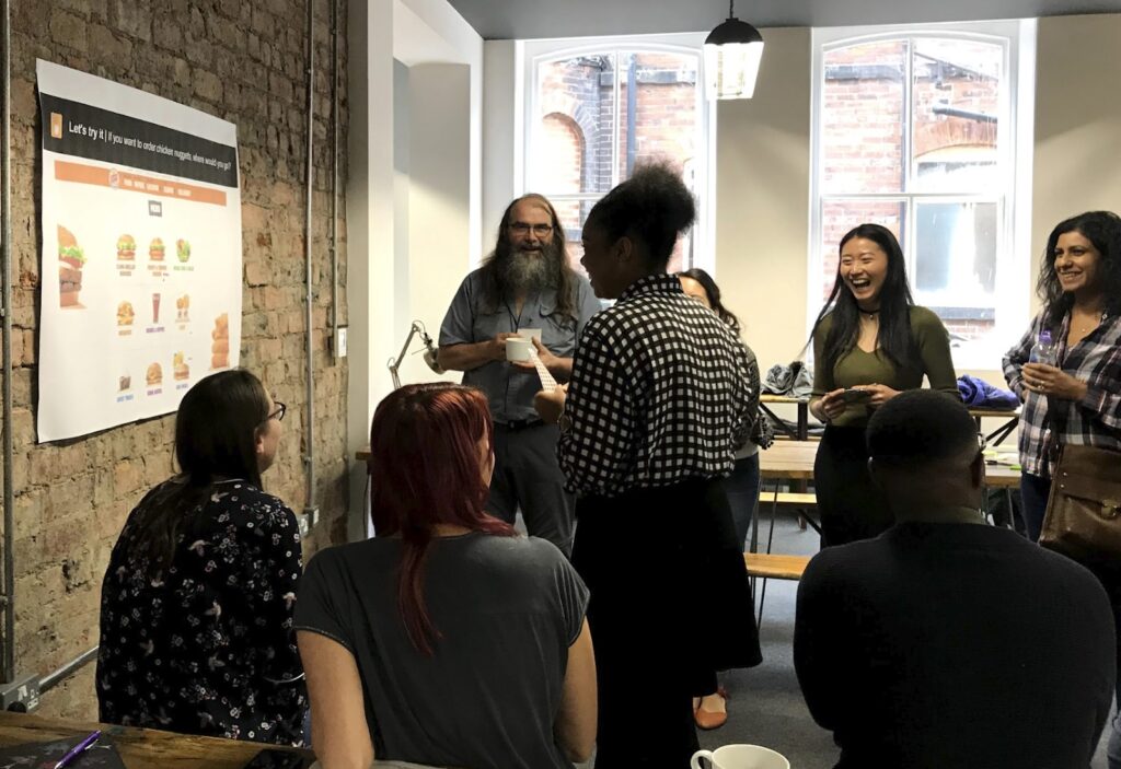 Male and female User Researcher standing in front of a poster having a discussion