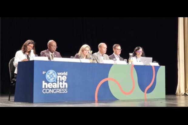 Pannel of six individuals sitting at a table with a