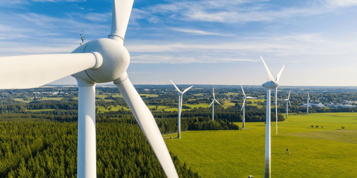 Wind Turbines In A Green Field With Blue Sky