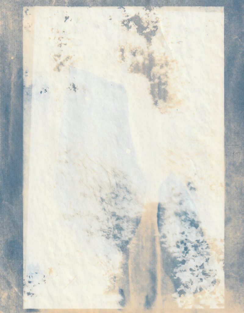 White impression of a photo on a mottled cream and blue cyanotype