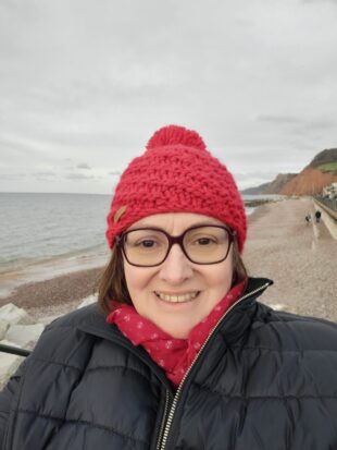 Sue wearing a red hat and black coat