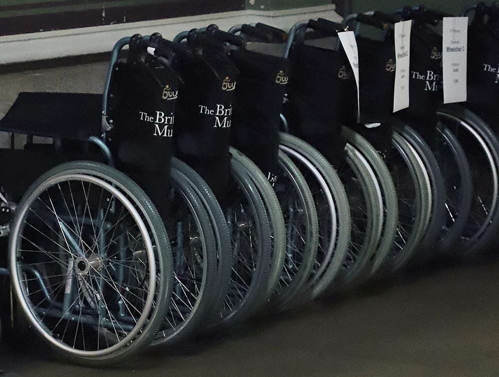 A row of seven folded up wheelchairs.  