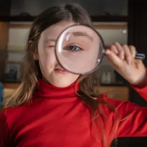 Girl looking at the camera through a magnifier