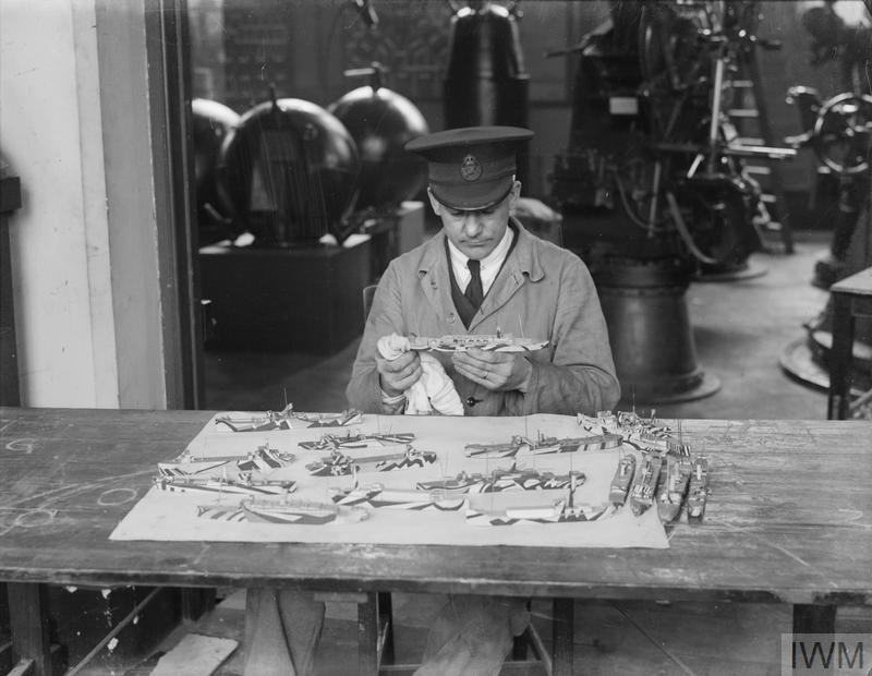 A person who works for IWM cleaning models of dazzle ships in 1926.