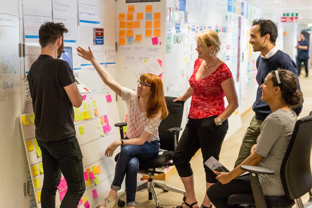group of people standing next to a board, discussing things