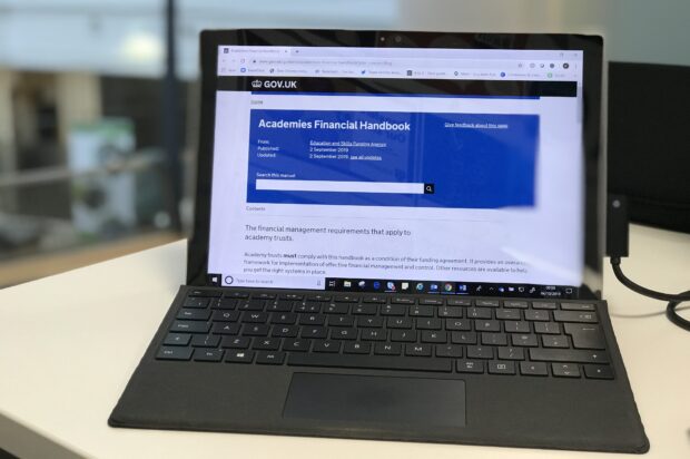 laptop screen showing Academies Financial Handbook GOV.UK page