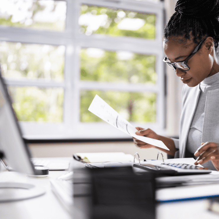 Project Control Lady In Glasses At A Computer With Papers And A Calculator