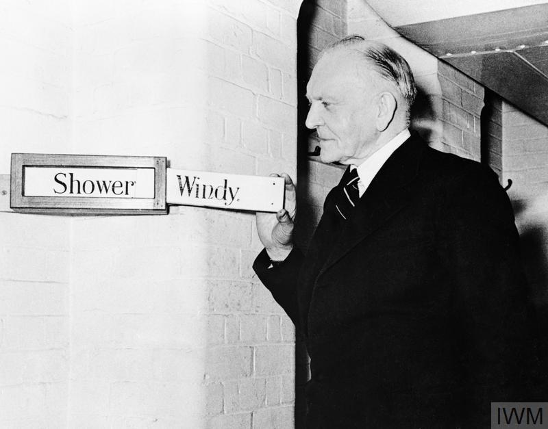 George Rance, Clerk and Custodian of the Cabinet War Rooms, smiles as he adjusts the weather indicator boards to 'windy'.
