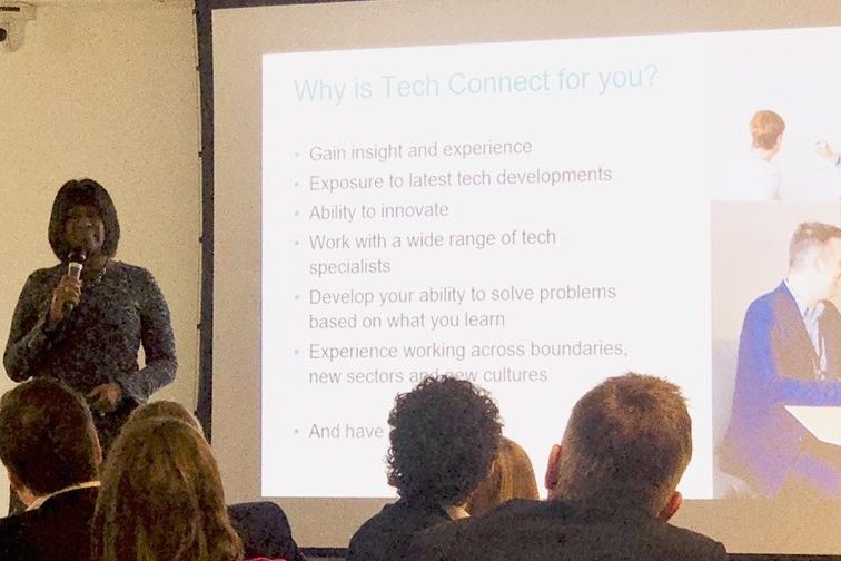 Jacky Wright standing in front of the TechConnect audience with slides on a screen to the side