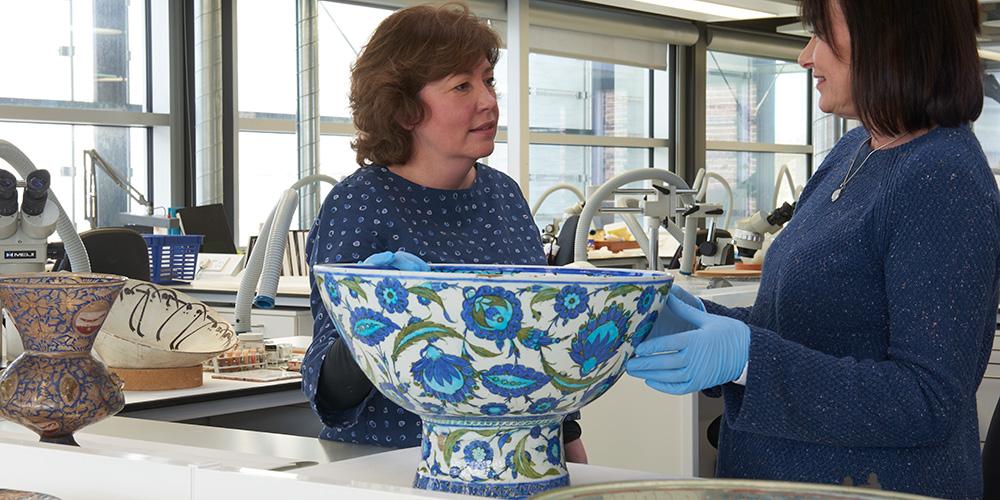 Denise Ling and Loretta Hogan (ceramic and glass conservators) assessing a large Iznik bowl.