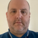 A close up of a man wearing a blue shirt