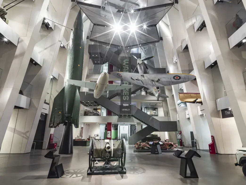 Large central atrium with a winding modern staircase climbing to the roof terrace beneath a glass roof.
