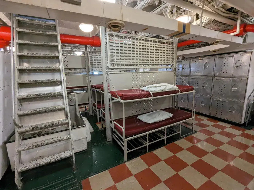 Spacious below deck sleeping quarters with bunks, washrooms, ladders, and port holes. 