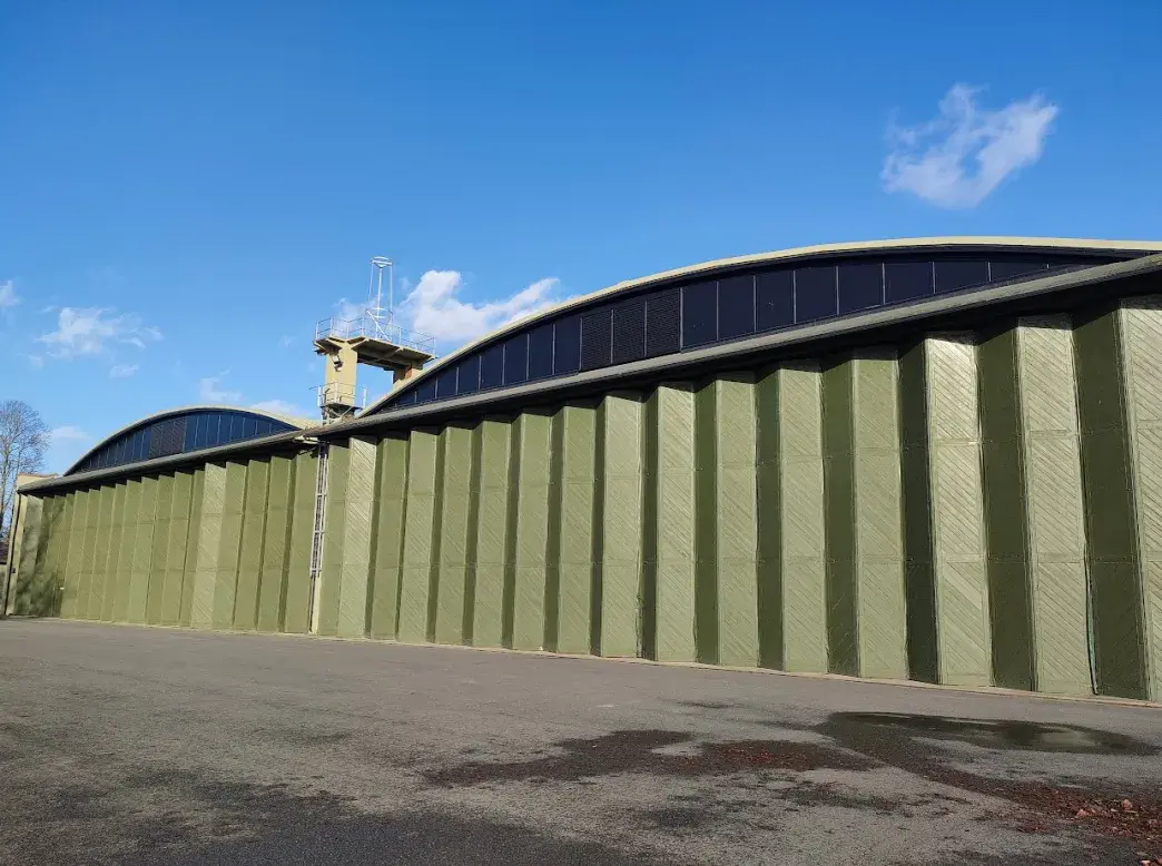 Exterior shot of Belfast type hanger with green folded wooden doors.