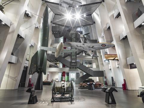 Large central atrium with a winding modern staircase climbing to the roof terrace beneath a glass roof.