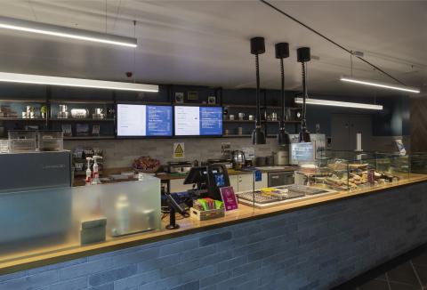 Cafe interior at IWM North showing counter, food items and menu.