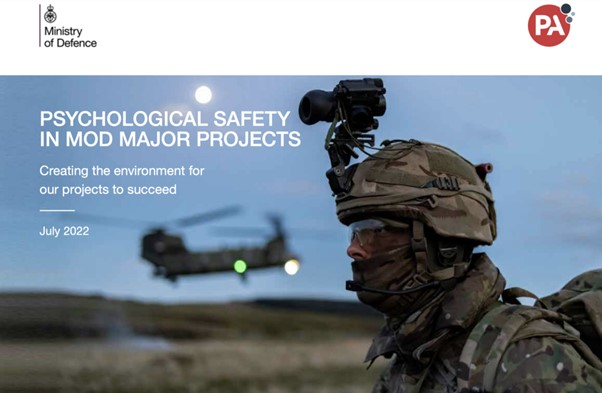 a soldier stands in front of a helicopter.