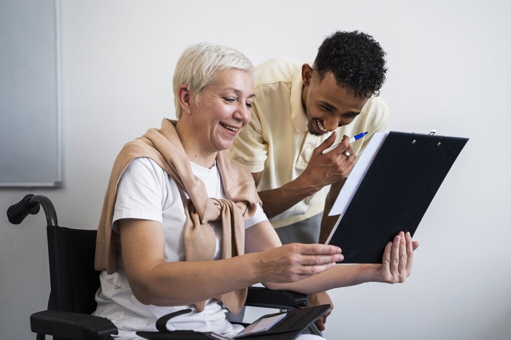 Woman in wheelchair and carer looking at a care plan.