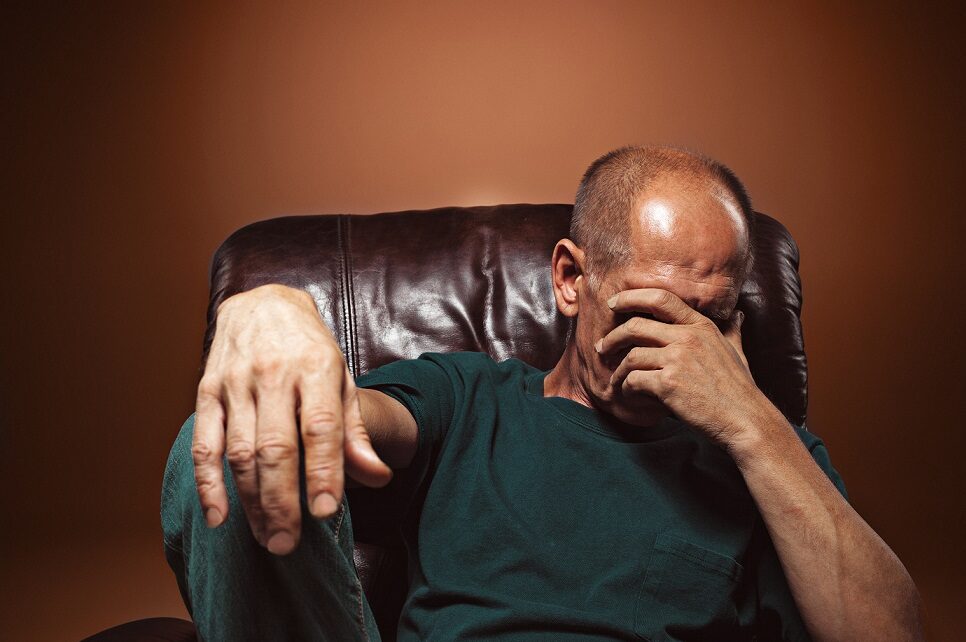 Man in chair looking worried and sad.