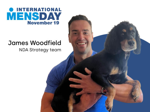 Man in blue t-shirt holding his dog in his arms