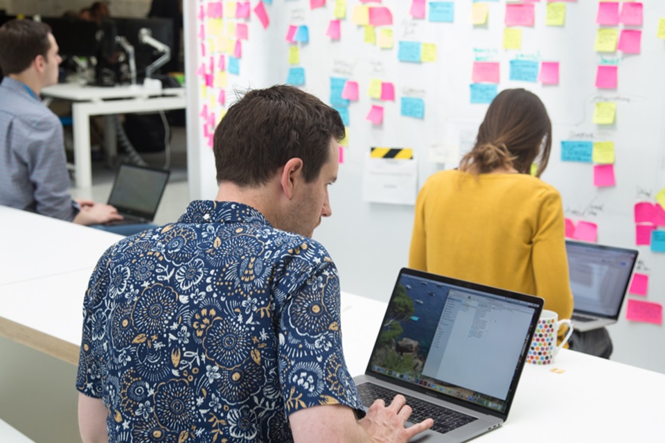 A man and a women with their backs to the camera working on their laptops