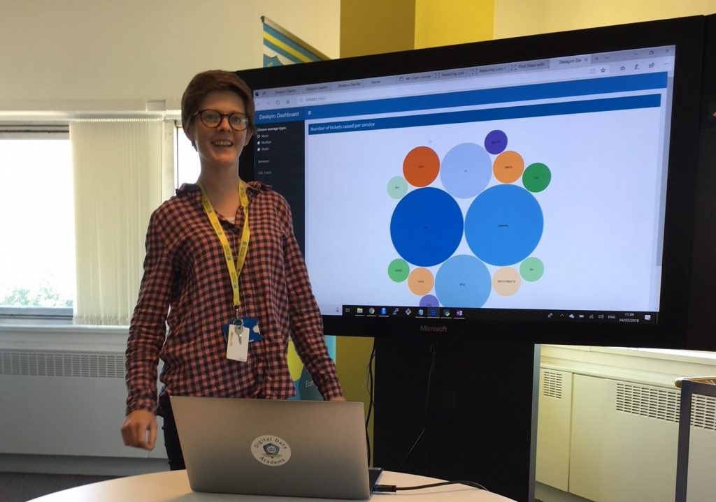 Data Scientist Emma McLarnon standing in front of a large display screen