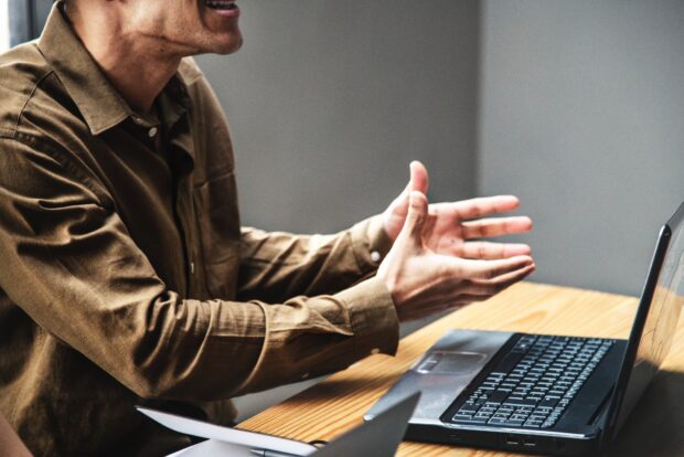 Man seated at desk - with open laptop - displaying attitude of exasperation