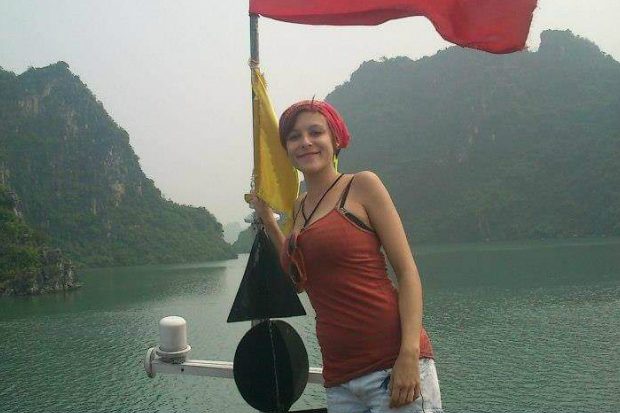 Natasha standing on a boat with hills behind her.