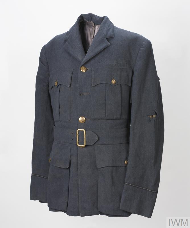 Single-breasted open-collared four-pocket jacket of RAF blue. The cuffs feature single rank braid rings (Pilot Officer) and all but one of the RAF officer quality crested buttons are present (one re-sewn by curator back in position (top) as it became detached during examination, 4/Dec/2009). The integral cloth belt fitted with brass open double-claw buckle it attached.