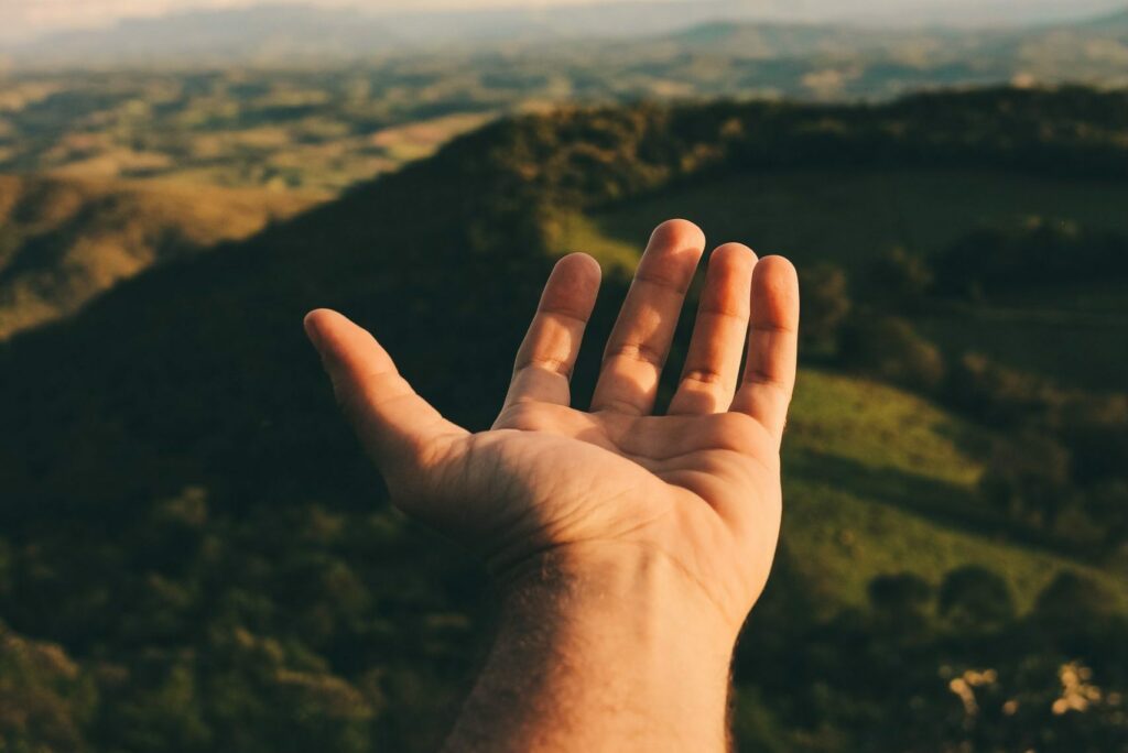 Hand reaching out towards blue sky