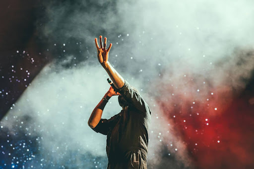 A performer singing into a microphone with blue and red lights in the background