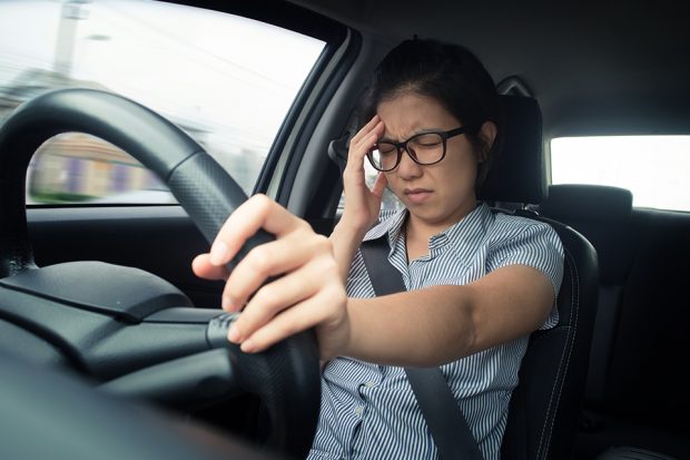Driver holding head at wheel of a vehicle