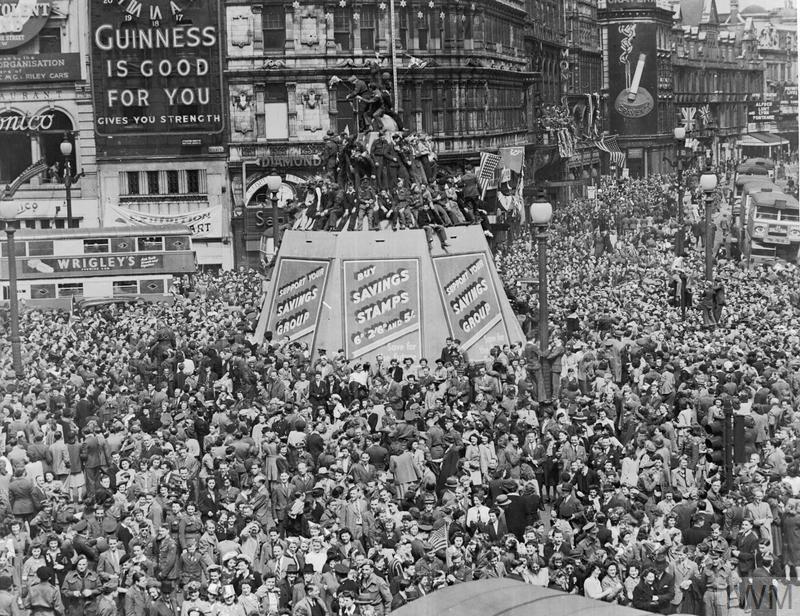 A mass of civilians and servicemen crowding around Piccadilly Circus, London.