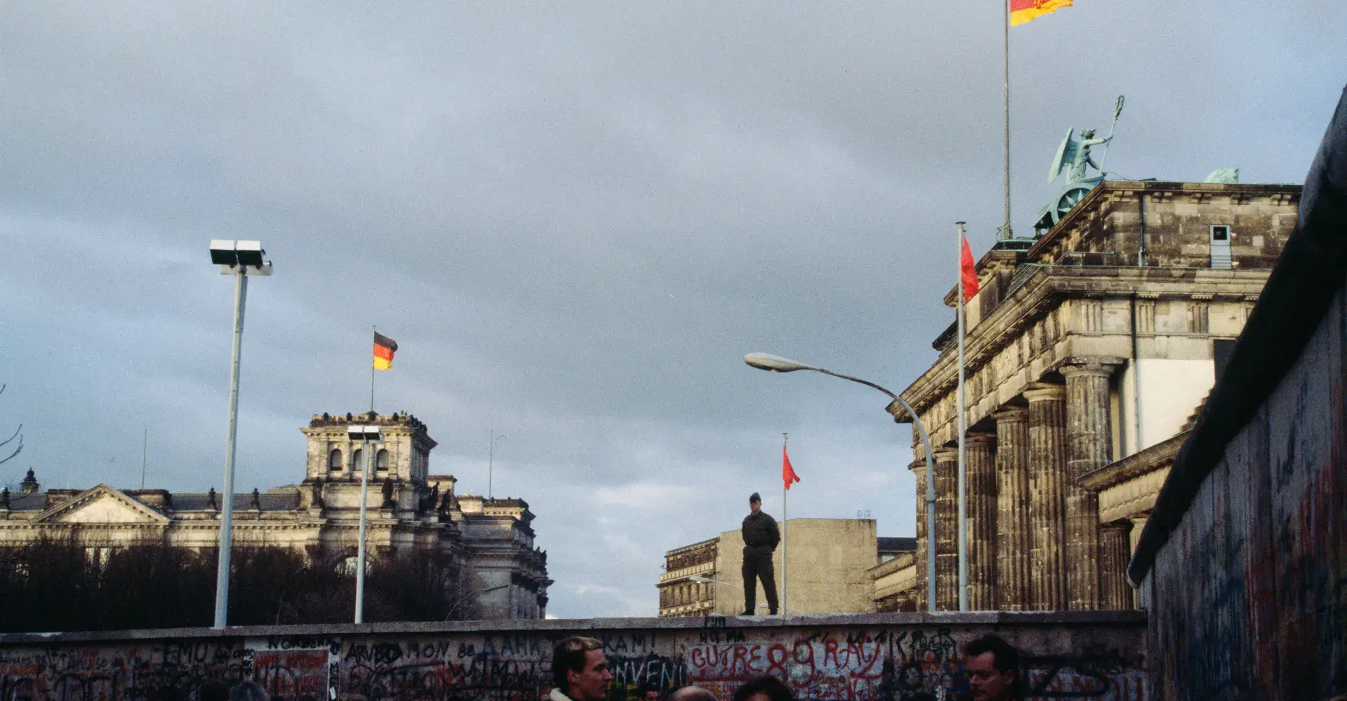 The opening of the Berlin Wall, November 1989. From his vantage point on top of the Wall adjacent to the Brandenburg Gate, an East German guard monitors the crowd below.