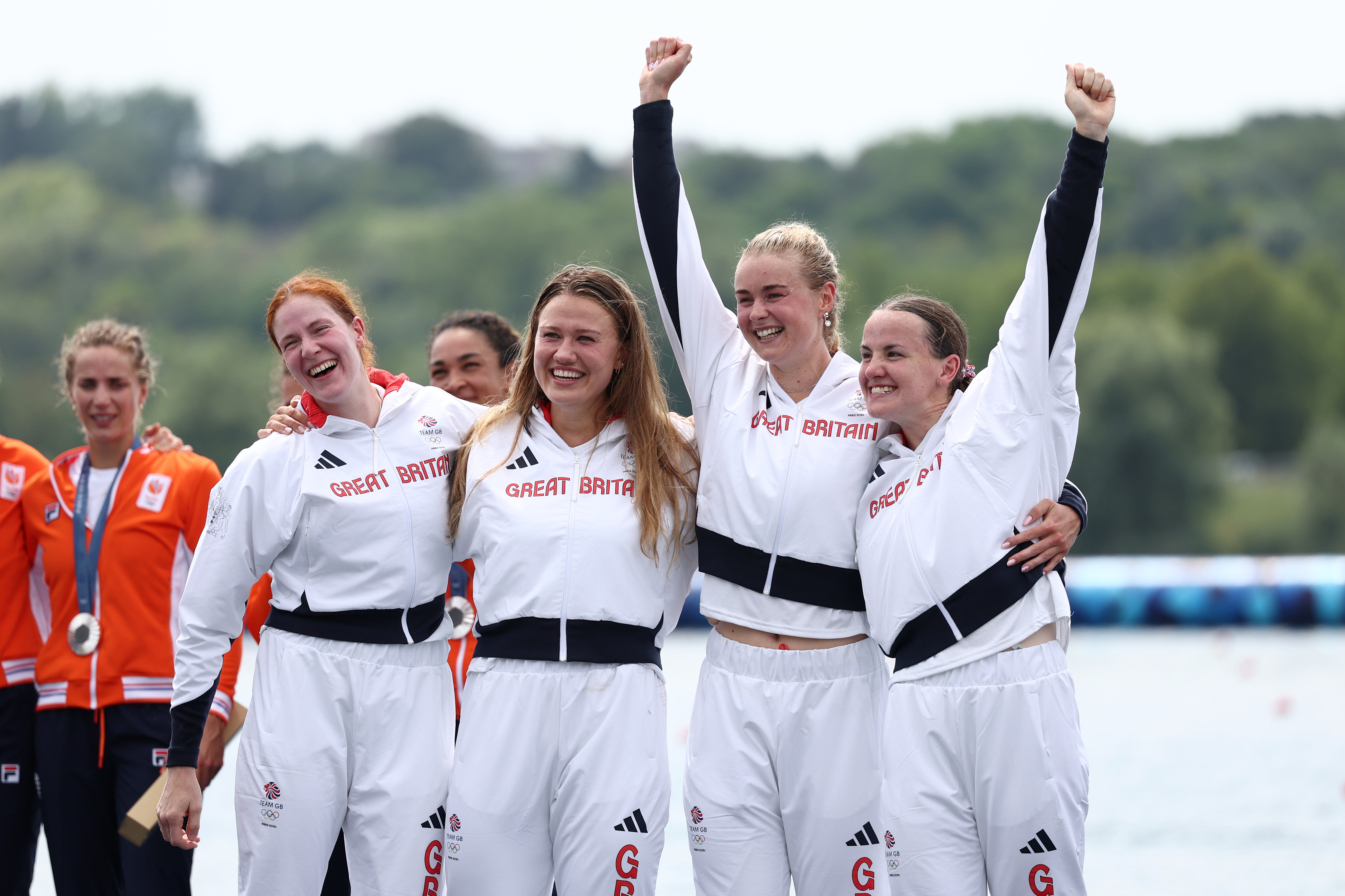 Four Team GB rowing athletes celebrating on the podium after winning gold the women's quad sculls 