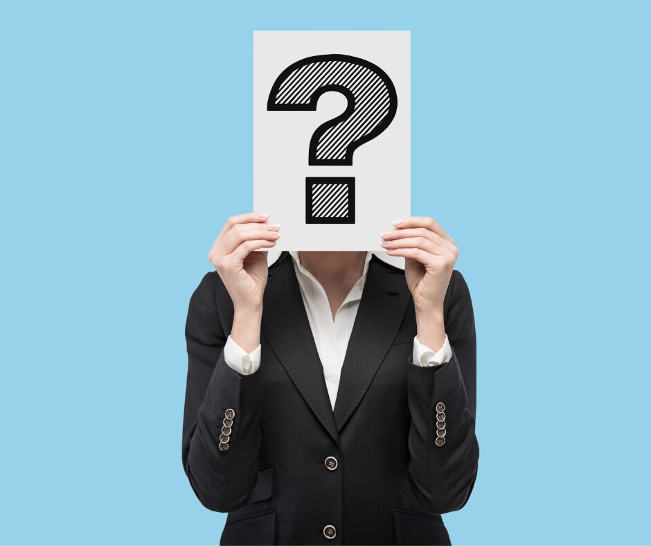 A person holding a sign with a question mark across it over their face