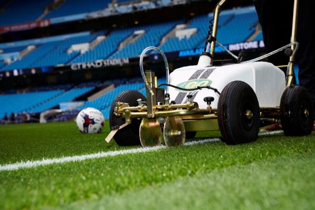 Linemarker painting the lines in a football stadium.
