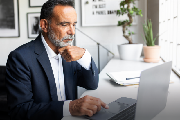 A man wearing a suit types on a laptop in a professional office setting