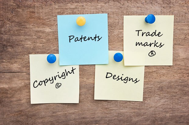notes pinned to a wooden board consisting of the words patents, trade marks, copyright and designs.
