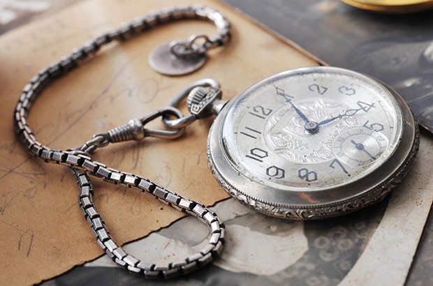Image of old clock/watch resting on old paperwork.