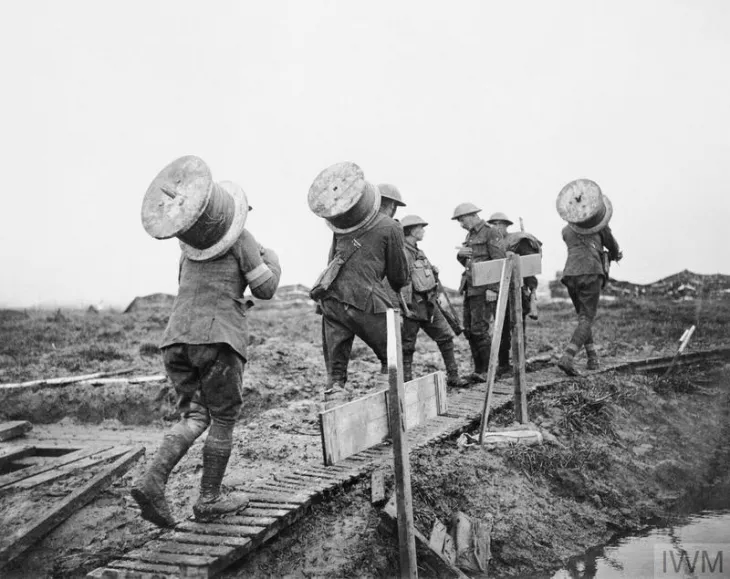 Battle of Poelcappelle. Royal Engineers taking drums of telephone wire along a duckboard path up to the front between Pilckem and Langemarck, 10 October 1917.