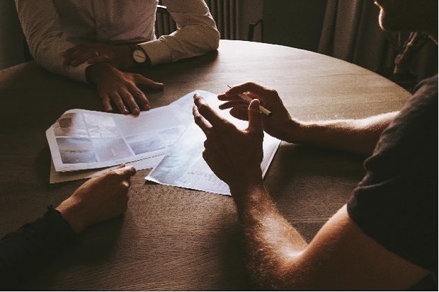 Three people sitting in a circle around a table with papers on it