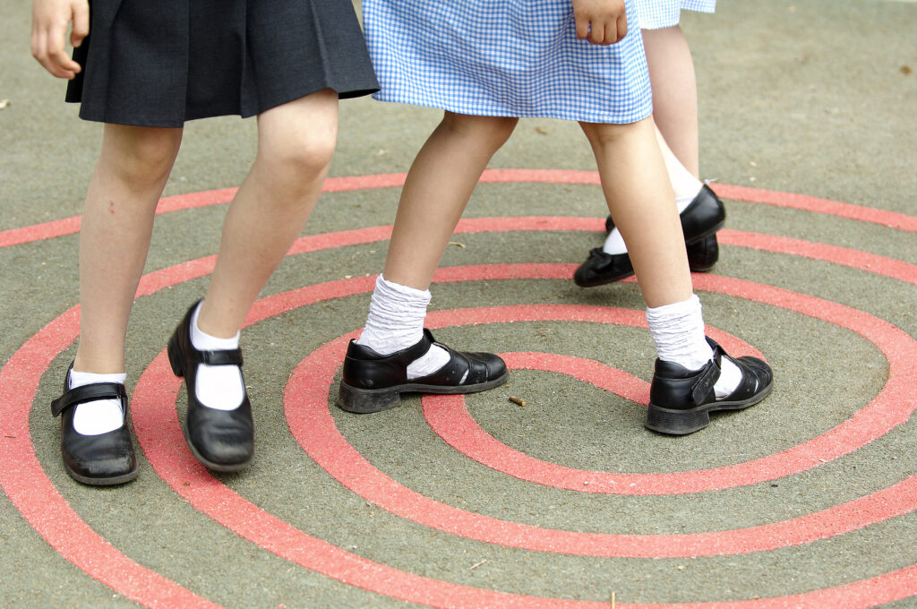 Unique ID: POSL720 Caption: A junior school playground. Break time. A group of children. Girls standing on a painted spiral on the ground. Year 5and 6 school. Running around. Letting off steam. Movement. Exercise and outdoor activity. Having fun. Restrictions: NHS Photo Library - for use in NHS, local authority Social Care services and Department of Health material only Copyright: ©Crown Copyright
